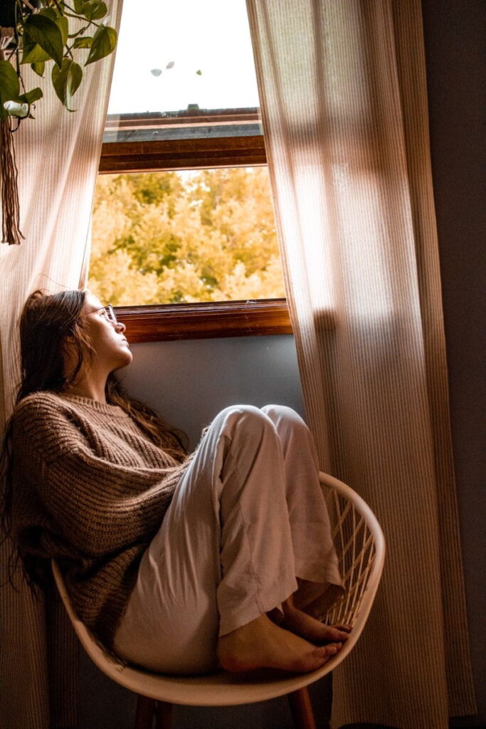 Frau schaut nachdenklich aus dem Fesnster